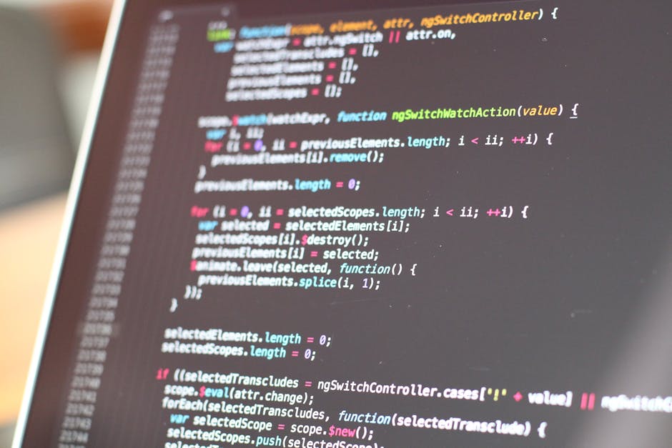 A close-up of a computer monitor displaying lines of colorful programming code with syntax highlighting, including keywords, variables, and functions in shades of blue, pink, green, and white. The bac